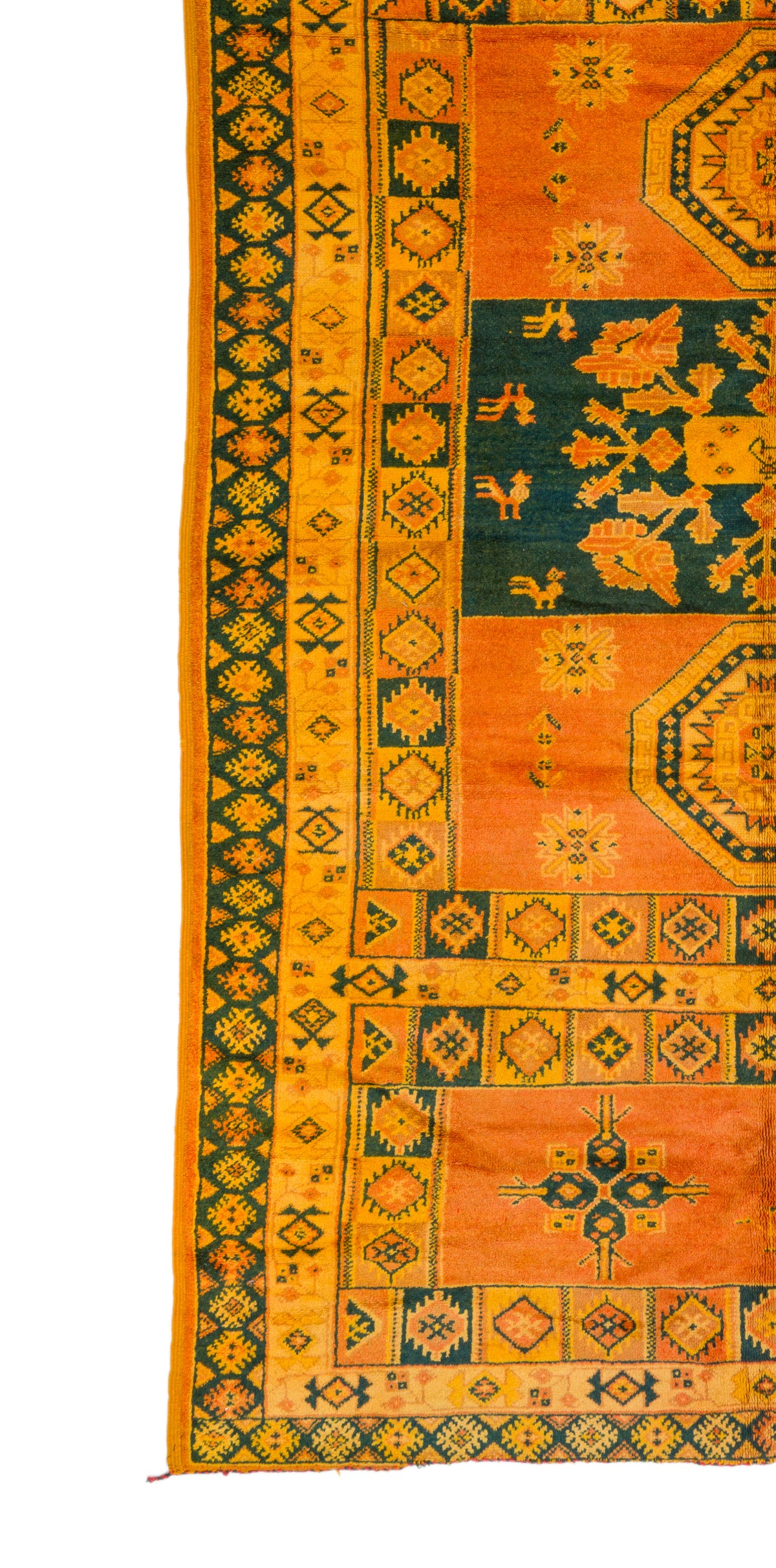 A close-up of a patterned rug or textile shown vertically, with orange and yellow fields, dark green sections, and geometric border motifs on a white background.