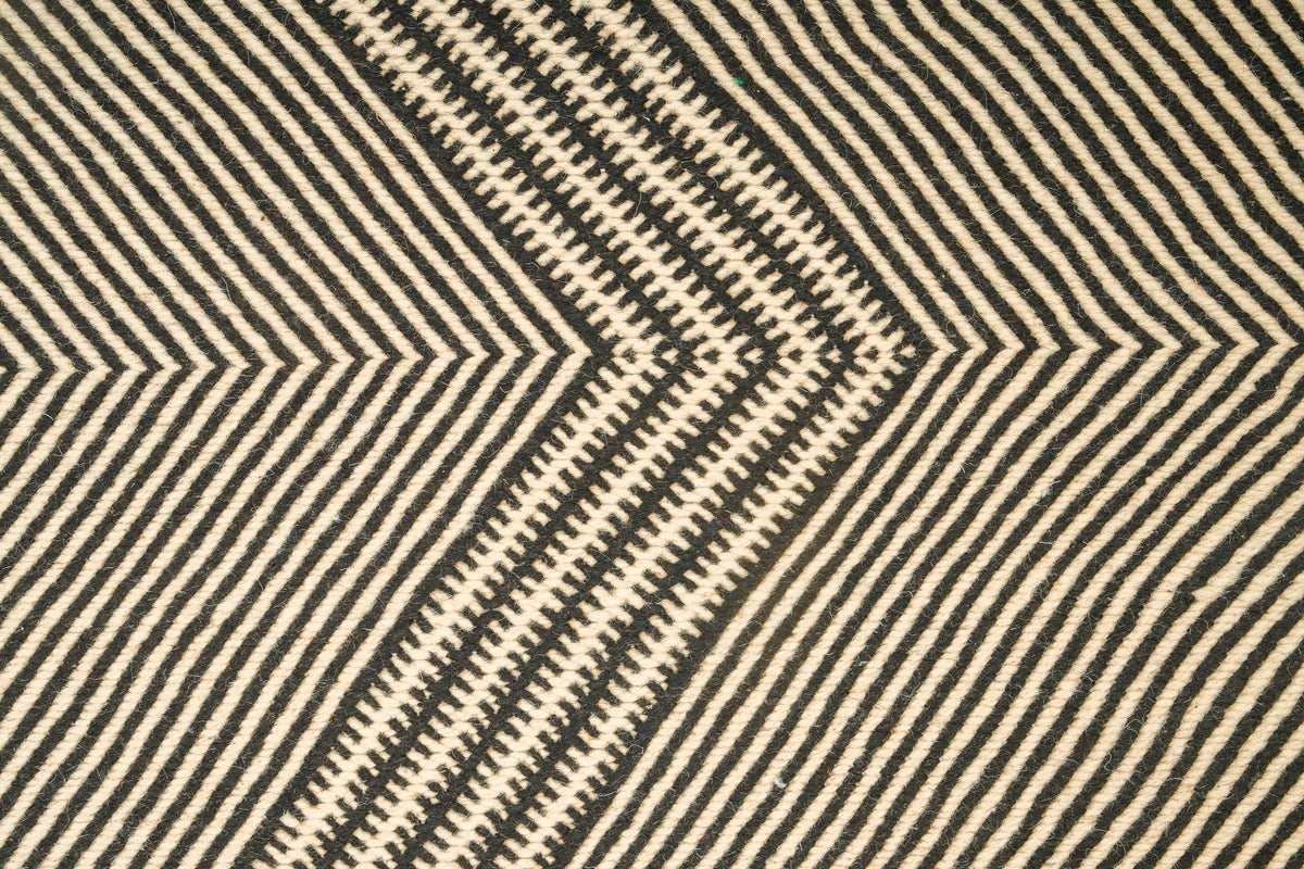 Close-up of a Moroccan Zanafi rug with a bold geometric chevron pattern in black and warm beige.