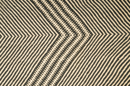 Close-up of a Moroccan Zanafi rug with a bold geometric chevron pattern in black and warm beige.