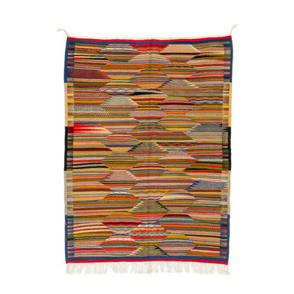 A rectangular woven moroccan rug with a geometric pattern of stacked, layered arches and stripes in multiple colors including red, blue, yellow, green, black, and beige, finished with white fringe on the bottom.