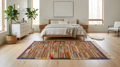 A colorful striped moroccan rug with fringe is styled in a bright, modern bedroom with light wood floors, a wooden bed, and white walls.