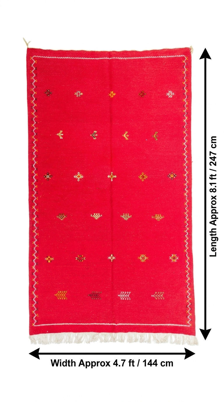 A red handwoven moroccan rug with small hand embroidered multicolor geometric motifs and a white fringe, shown with dimension arrows indicating a width of approximately 4.7 ft (144 cm) and a length of approximately 8.