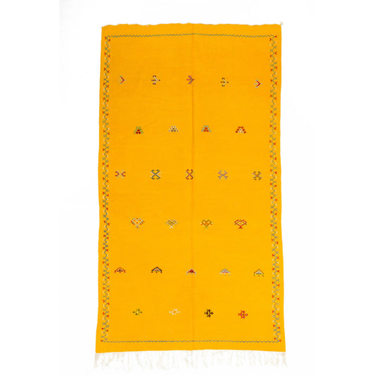 A bright yellow Moroccan wool rug with a hand-woven geometric border and small colorful embroidered motifs, shown flat against a white background.