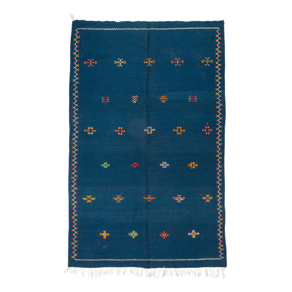 A rectangular blue moroccan rug with a hand embroidered geometric pattern of small colorful diamond motifs and white fringe at the top and bottom, shown flat against a white background.