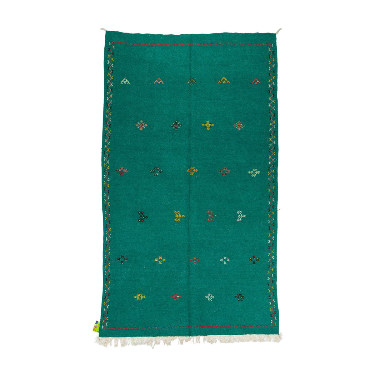 A rectangular emerald green moroccan rug handwoven with a white fringe at the bottom, decorated with small embroidered multicolored geometric motifs and bordered by a patterned edge, shown flat against a white background.