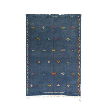 A rectangular blue wool moroccan rug with a hand-woven geometric motifs and fringed edges, displayed flat against a white background.
