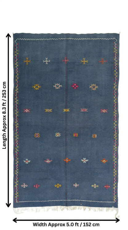 A denim blue moroccan wool rug with colorful embroidered geometric patterns and fringe, shown with dimension lines indicating a length of approximately 8.3 ft (253 cm) and a width of approximately 5.