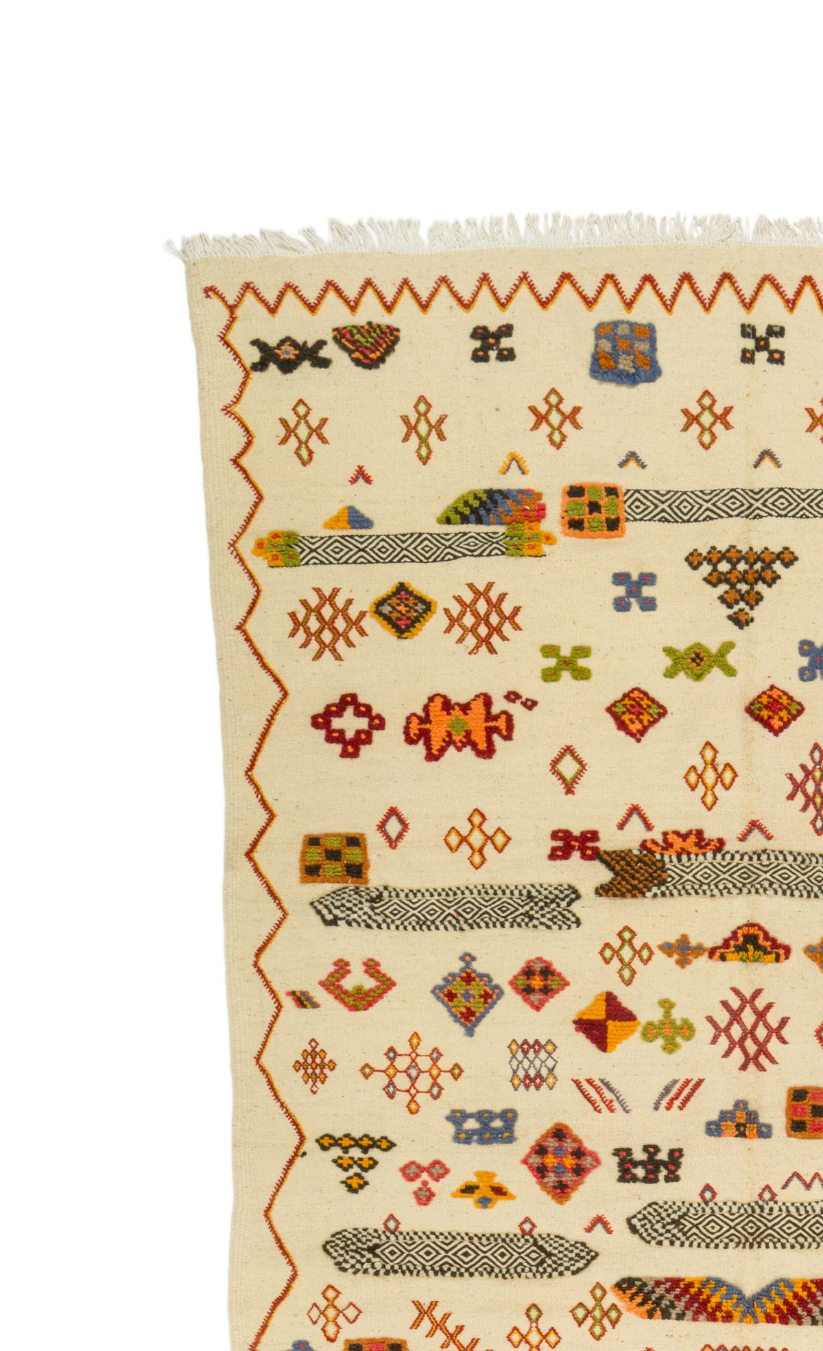 A close-up of a woven rug with a cream base and a multicolor geometric pattern, featuring orange zigzag borders and small stylized motifs.