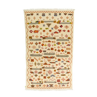 A rectangular handwoven kilim rug with a cream background and intricate multicolor geometric patterns, featuring fringed edges.