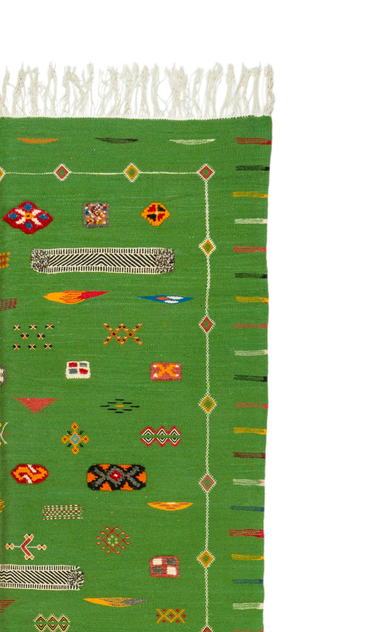 A close-up of a green woven rug with white fringe at the top and multicolored geometric and striped patterns running vertically and horizontally.