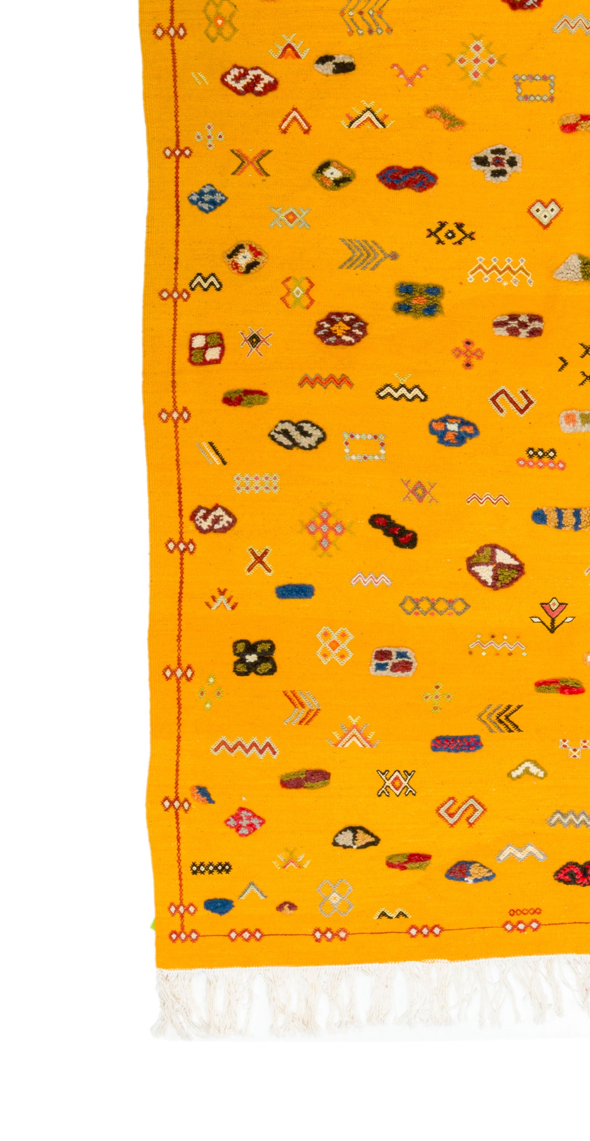 A close-up of a bright yellow rug with a white fringed edge and an allover scattered pattern of small multicolored geometric and abstract motifs.