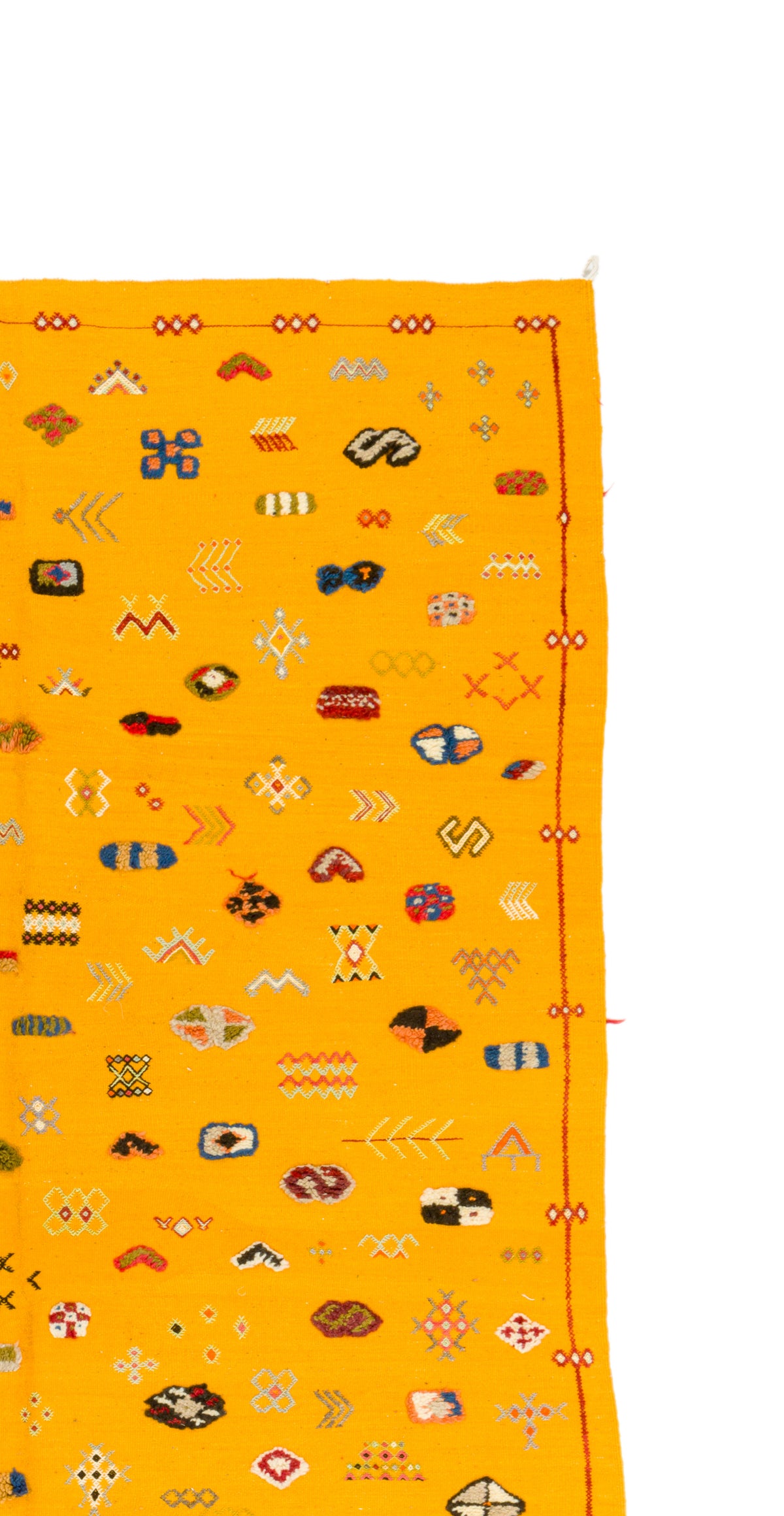 A close-up of a bright yellow rug with an allover pattern of small multicolored geometric and tribal-style motifs, shown against a white background.