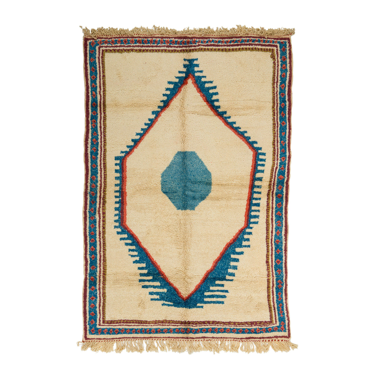 A rectangular wool hand-woven rug with a cream-colored base, featuring a central blue geometric diamond pattern outlined in red, surrounded by a patterned border and fringed edges. The rug is a moroccan rug.