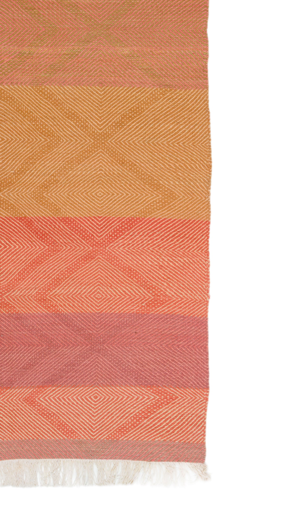 A close-up of a Moroccan Rug with horizontal bands of terracotta, mustard, coral, and dusty rose, featuring geometric diamond patterns and white fringe at the bottom, shown against a white background.