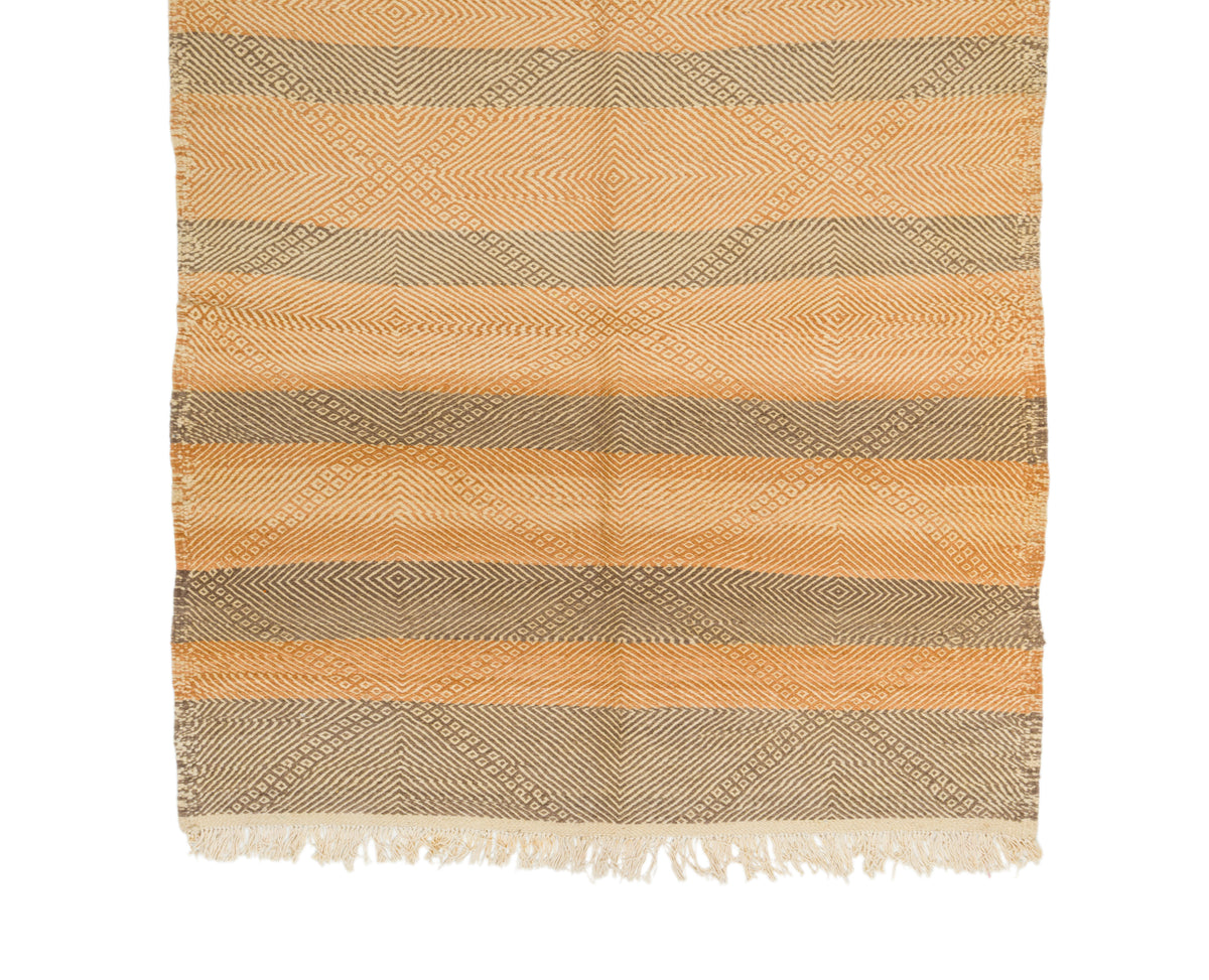 A Moroccan rug with horizontal stripes in warm tan, beige, and cream, featuring a textured geometric pattern and fringed edges.