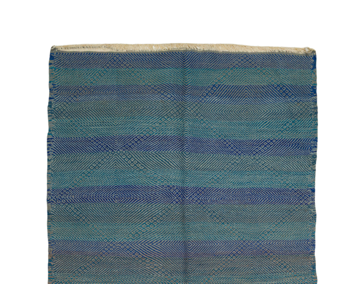 A Zanafi rug featuring a textured geometric diamond pattern in horizontal stripes of blue, teal, and beige on a white background.
