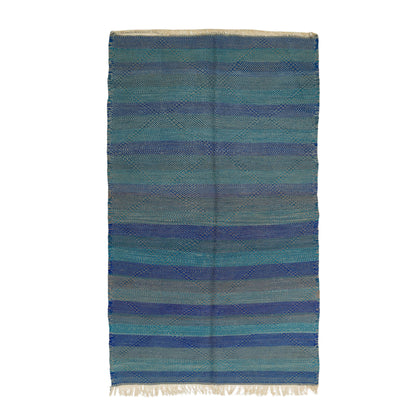 A rectangular woven textile with horizontal stripes in shades of blue, teal, and gray, finished with cream fringe on the bottom edge, shown flat against a white background.