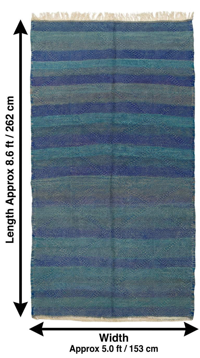 A rectangular woven rug with horizontal blue, teal, and gray stripes and fringe on the top and bottom edges, shown with dimension arrows and labels indicating approximately 8.6 ft by 5.