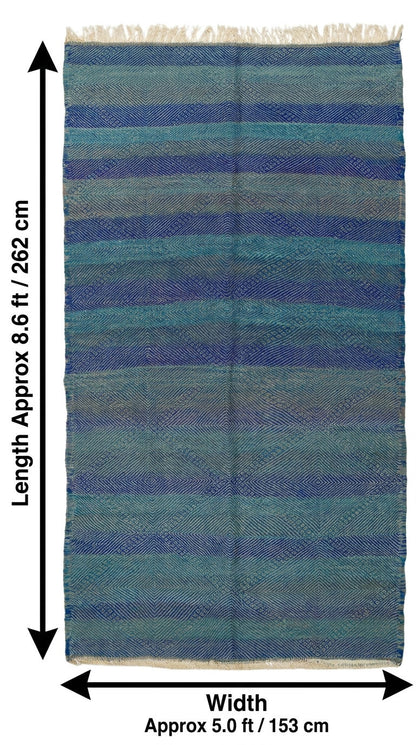 A rectangular woven rug with horizontal blue, teal, and gray stripes and fringe on the top and bottom edges, shown with dimension arrows and labels indicating approximately 8.6 ft by 5.