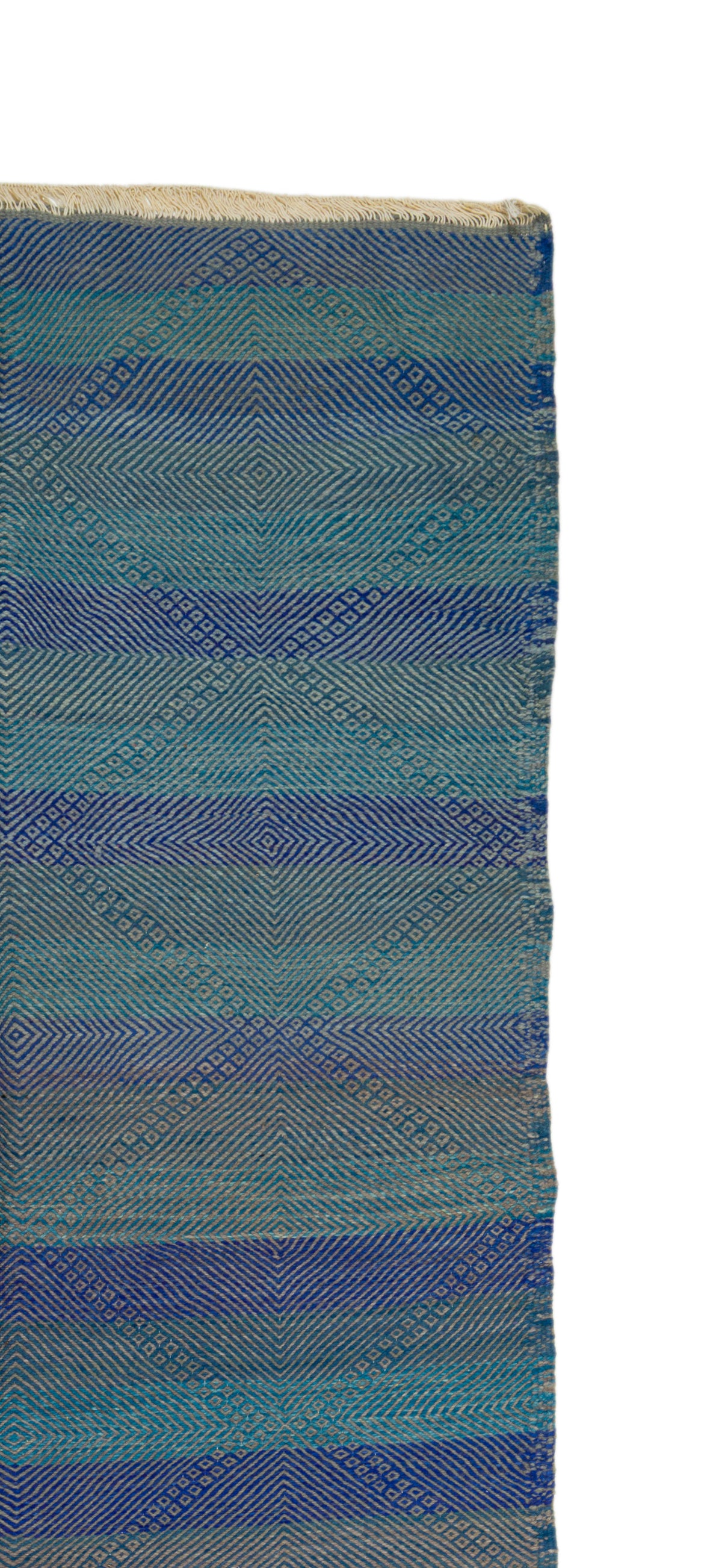 A close-up of a Moroccan rug with horizontal stripes in shades of blue, teal, and gray, showing a textured diamond pattern and a frayed edge.