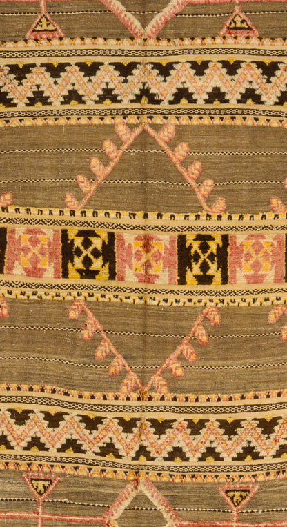 A close-up of a vintage moroccan kilim rug with horizontal bands and geometric patterns in olive green, black, beige, pink, and yellow.