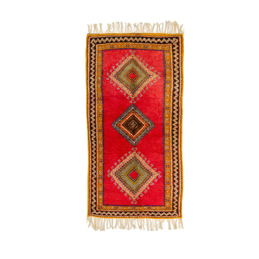 This one-of-a-kind 1970s vintage Moroccan wool runner rug was hand-knotted by a Berber woman artisan in the High Atlas Mountains of Morocco using traditional Taznakht rug-making techniques.