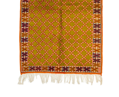 A Moroccan vintage rug with fringe, featuring a mustard yellow center with a repeating diamond lattice pattern in orange, white, and red, bordered by a multicolor geometric pattern and white tassels.