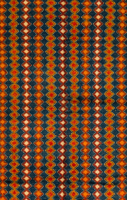 A close-up of a patterned Taznakht vintage rug featuring vertical columns of repeating diamond motifs in orange, red, cream, and dark navy blue.