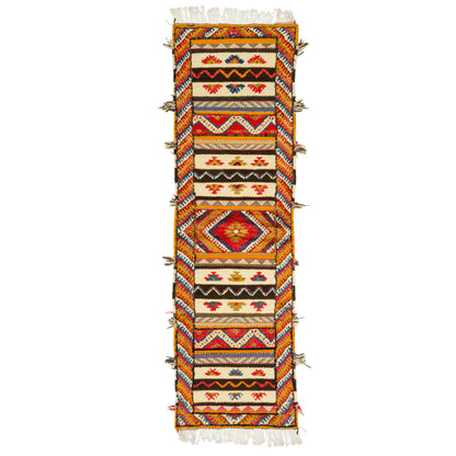 A long rectangular woven Glaoui Moroccan rug or runner with fringe on both ends, featuring a bold geometric and tribal-inspired pattern in orange, red, black, cream, and blue on a white background.