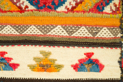 Close-up of a colorful Glaoui rug from Morocco with horizontal bands, geometric triangle motifs, and stylized floral or bird-like embroidery in red, blue, yellow, orange, black, and cream.