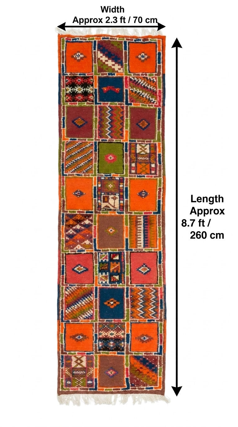 A tall, narrow patchwork rug with geometric and tribal patterns in orange, red, brown, green, and blue, shown with dimension arrows and text indicating a width of approximately 2.3 ft (70 cm) and a length of approximately 8.7 ft.
