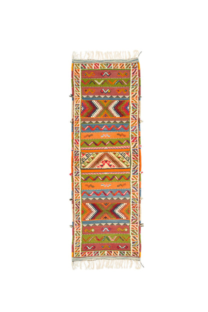 A long, narrow runner Glaoui rug from Morocco with a colorful geometric tribal pattern, featuring cream fringe on both ends, displayed flat against a solid white background.