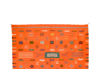 An orange Moroccan woven rug with geometric patterns and colorful accents, shown against a plain white background.