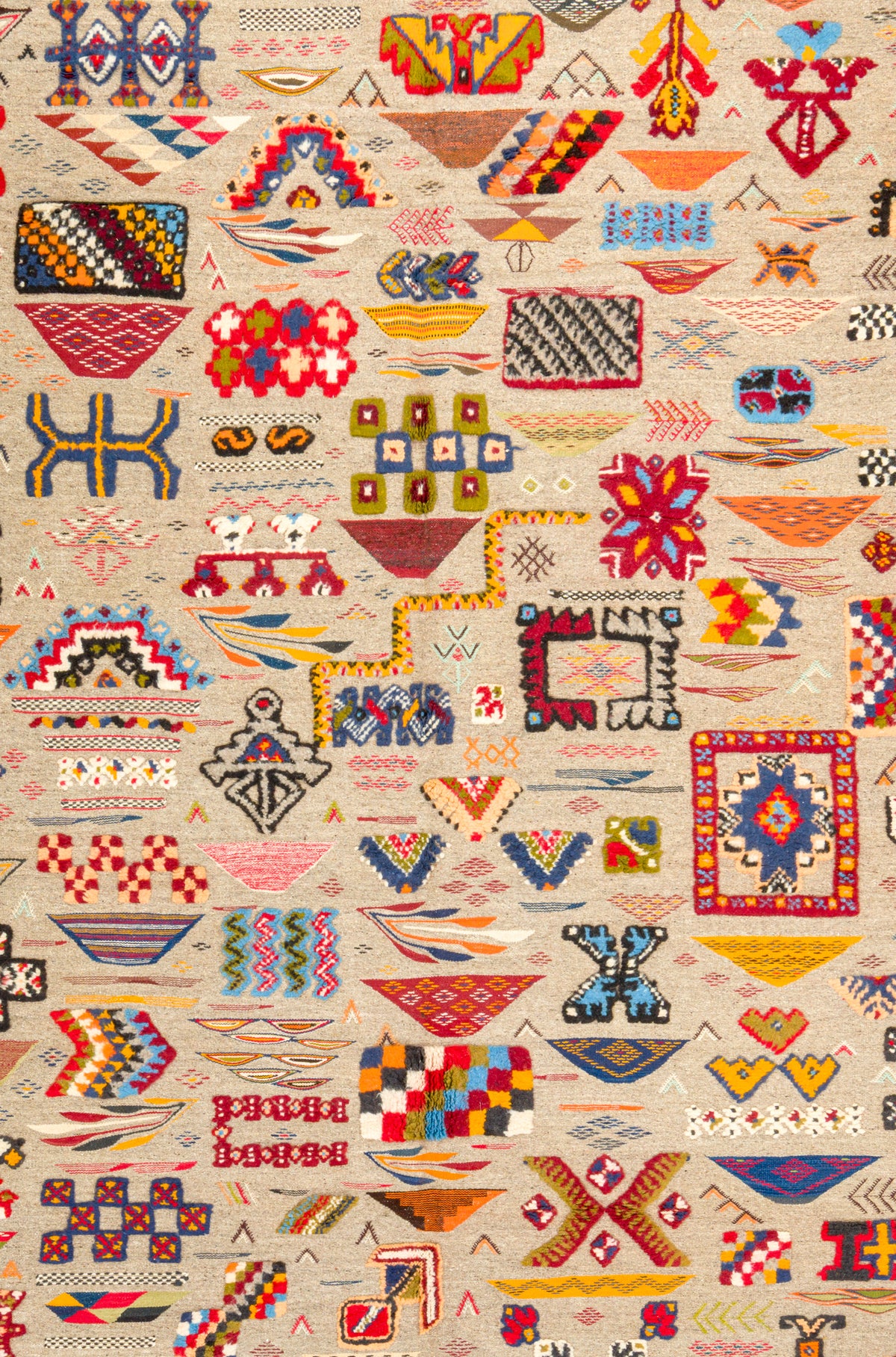 A close-up of a wool kilim rug from Morocco featuring a dense, colorful geometric pattern on a light beige background. The design includes various tribal-inspired motifs such as diamonds, zigzags, and blocks in red, blue, yellow, green, orange, and black.