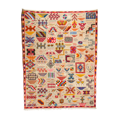 A Moroccan kilim rug with a cream-colored field and a red border, decorated with numerous colorful geometric and tribal patterns.