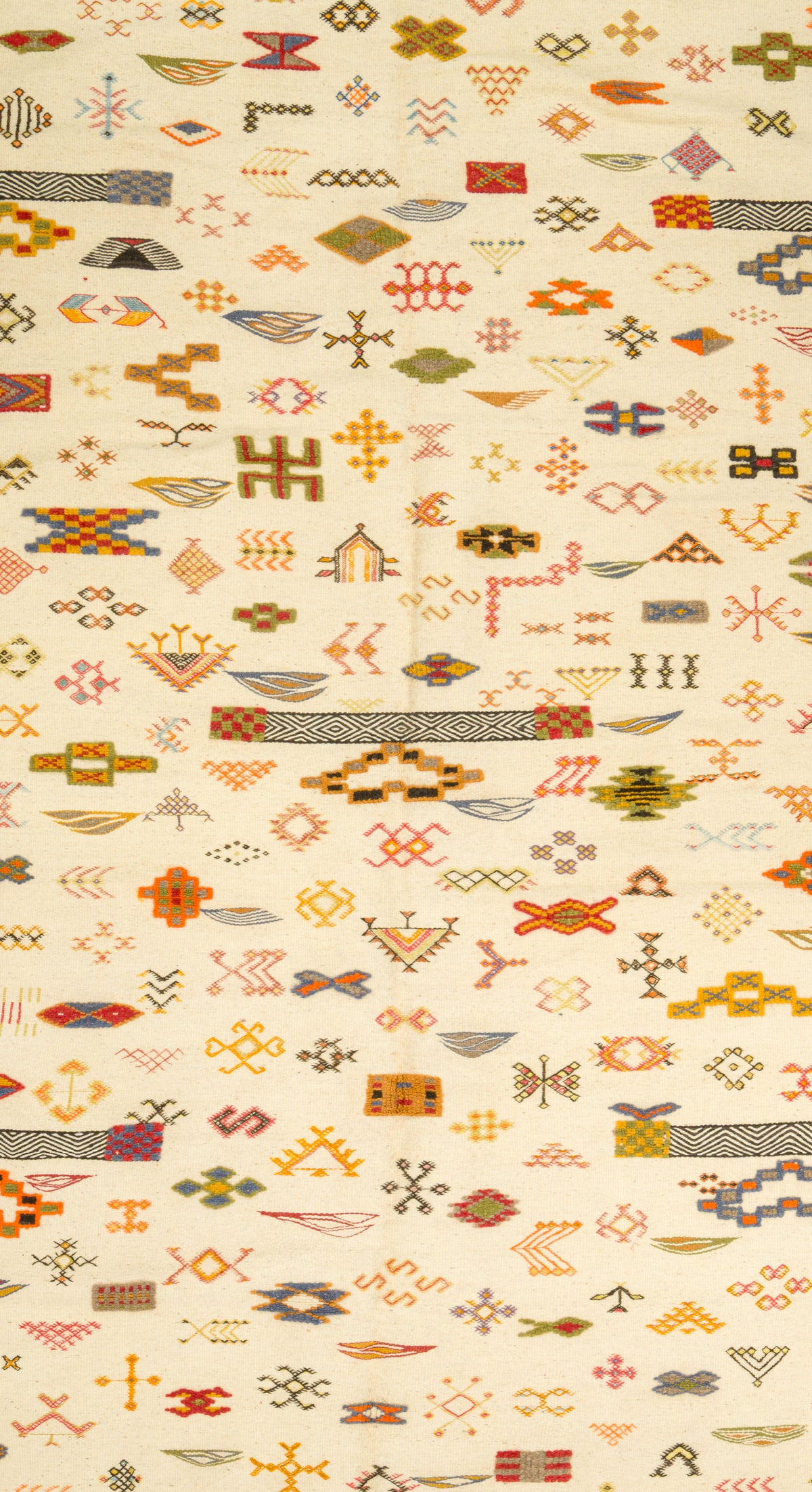 A close-up of a Moroccan with a dense, repeating geometric pattern in orange, brown, olive green, and red on a warm cream background.