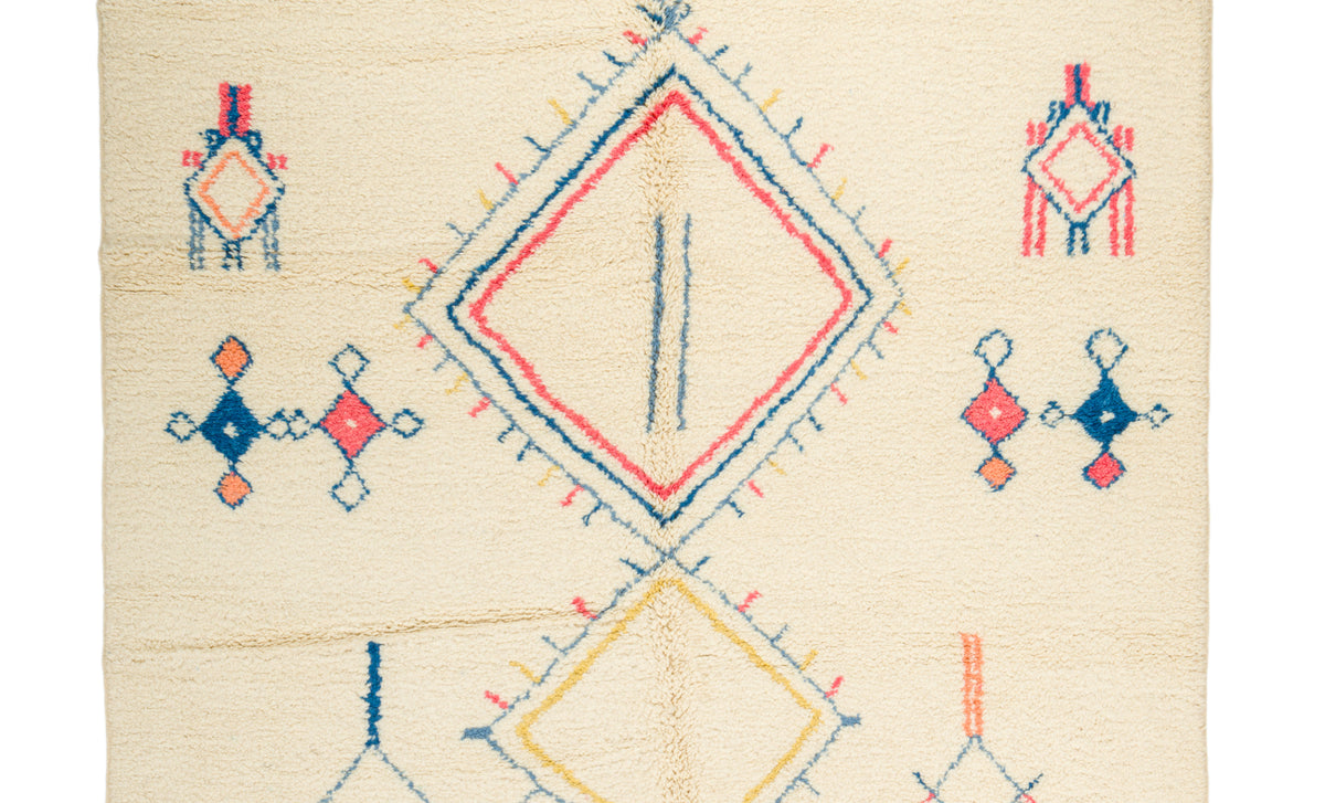 A square cream-colored Moroccanrug with a geometric pattern featuring a large central diamond, smaller diamond motifs, and embroidered-like stitched details in red, blue, and yellow.
