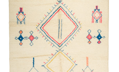 A square cream-colored Moroccanrug with a geometric pattern featuring a large central diamond, smaller diamond motifs, and embroidered-like stitched details in red, blue, and yellow.