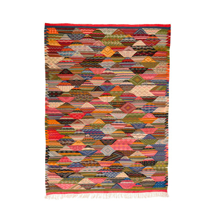 A rectangular woven moroccan rug from Taznakht with a colorful cubist diamond pattern, featuring a red border and white fringe at the bottom, shown flat against a white background.