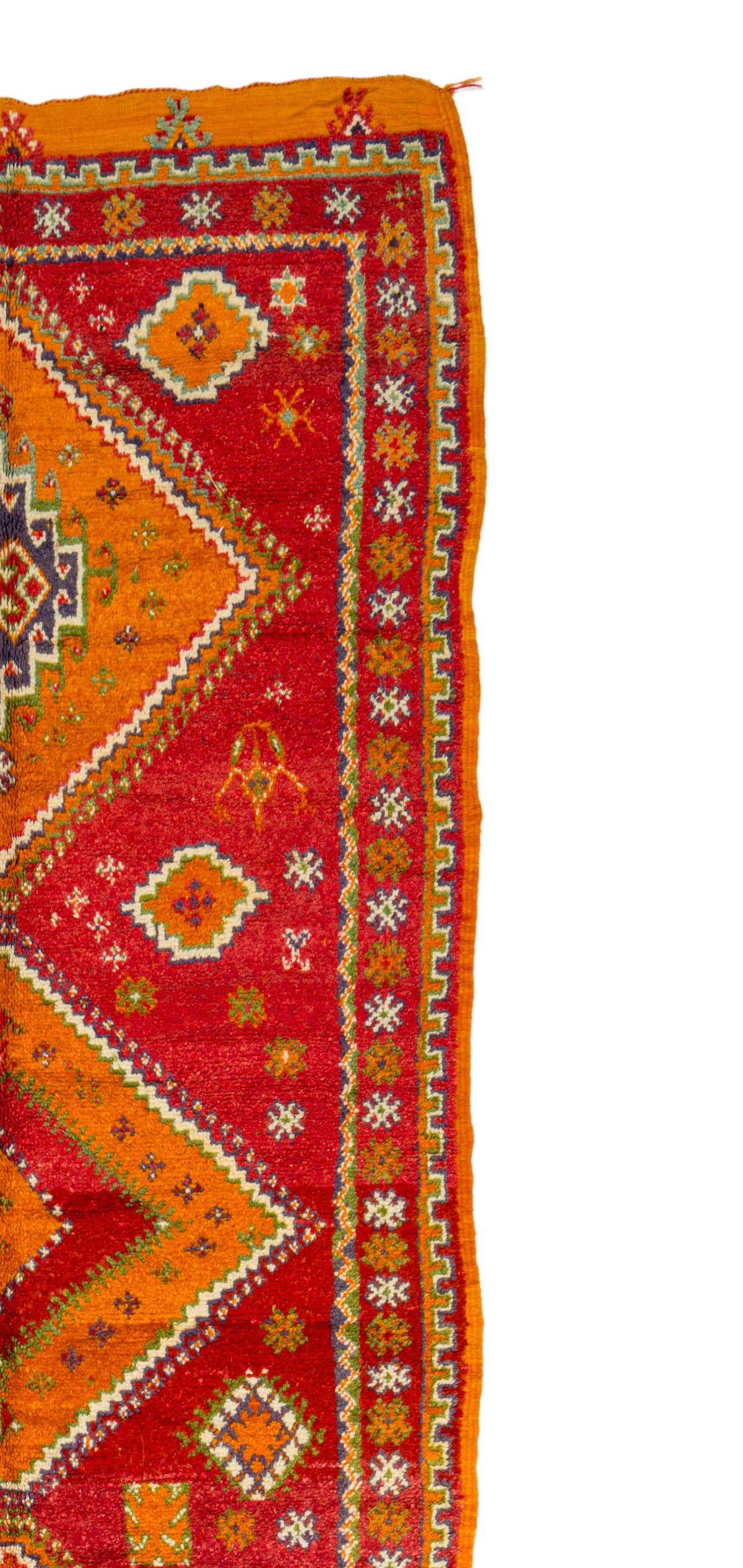A close-up of a patterned rug corner showing a red and orange geometric design with white and yellow details, photographed against a white background.