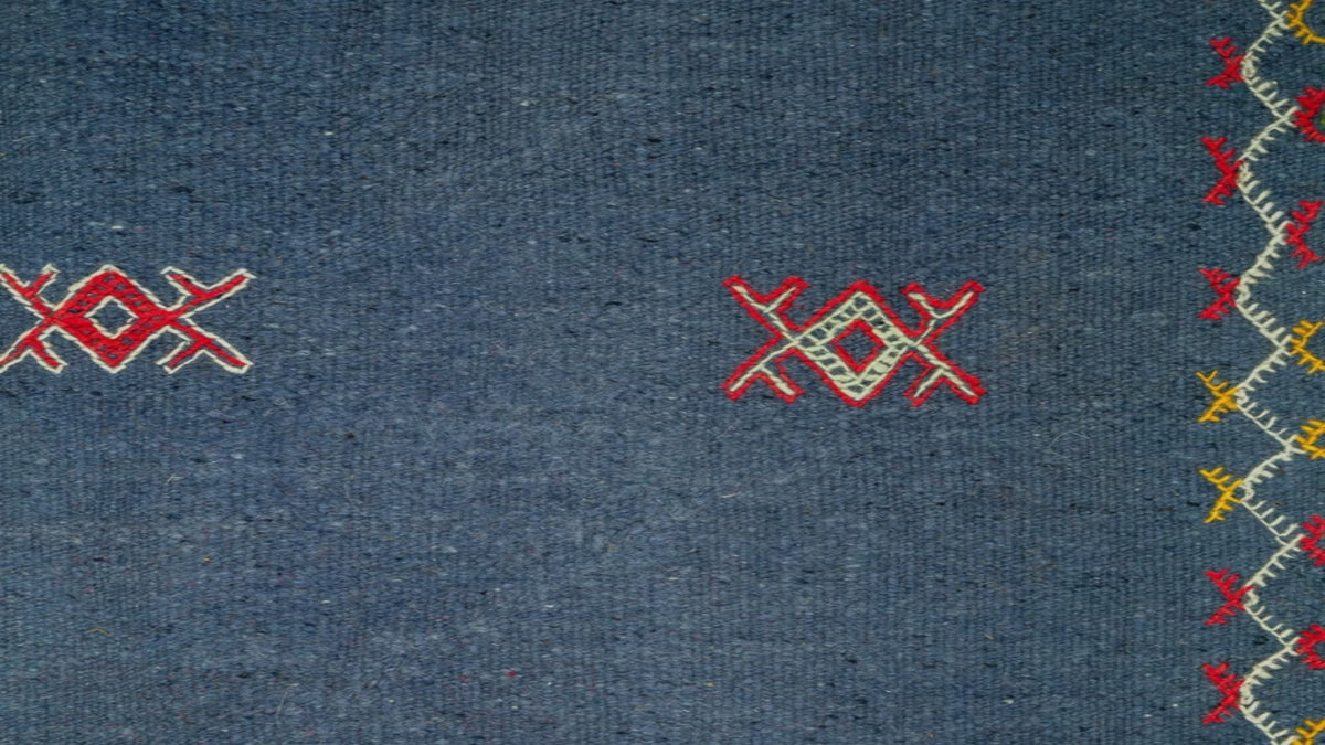 close-up view of a blue moroccan rug handwoven with hand embroidered tribal motifs