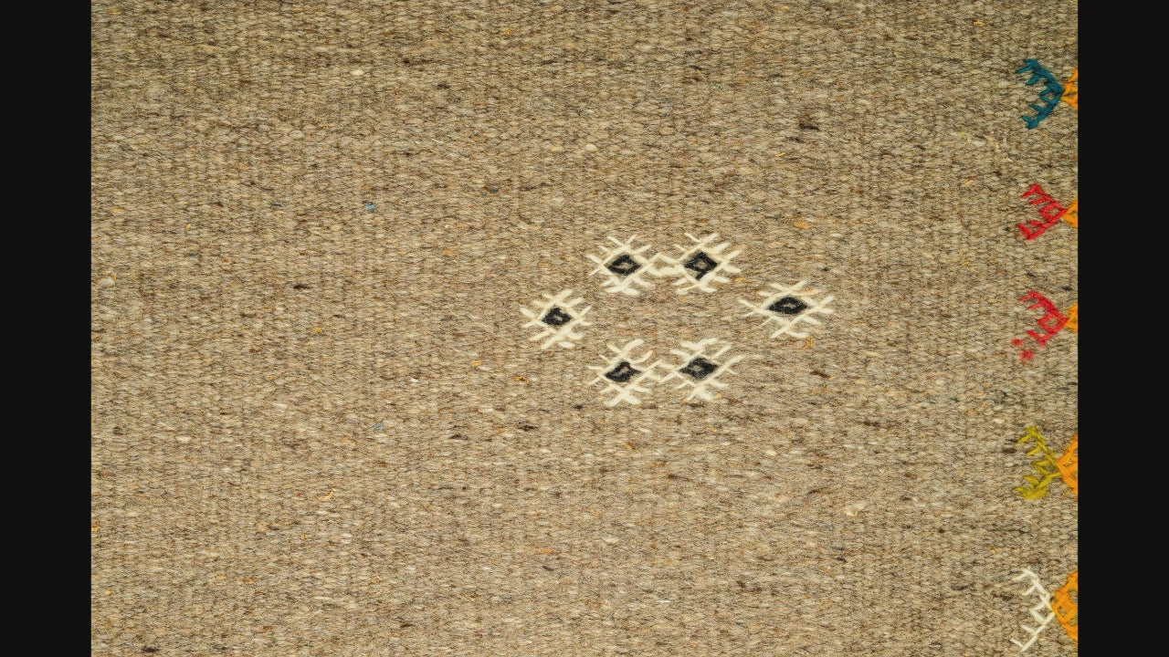 close-up video of a moroccan rug handwoven and hand embroidered with  small tribal motifs
