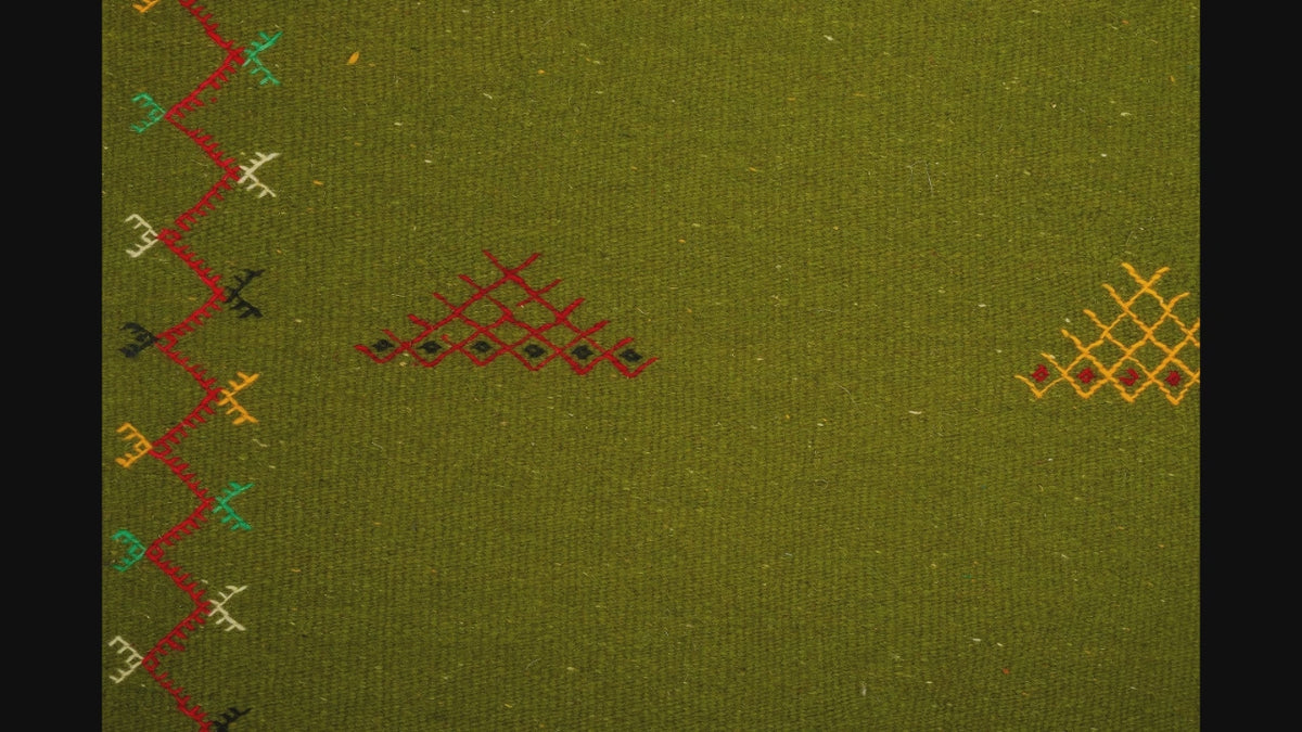 close-up video of green moroccan rug handwoven and hand embroidered with tribal motifs