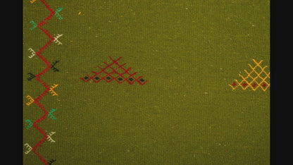 close-up video of green moroccan rug handwoven and hand embroidered with tribal motifs