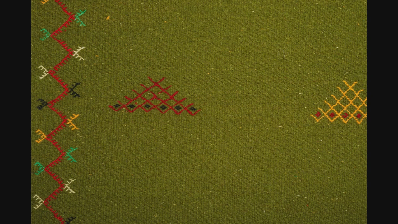 close-up video of green moroccan rug handwoven and hand embroidered with tribal motifs