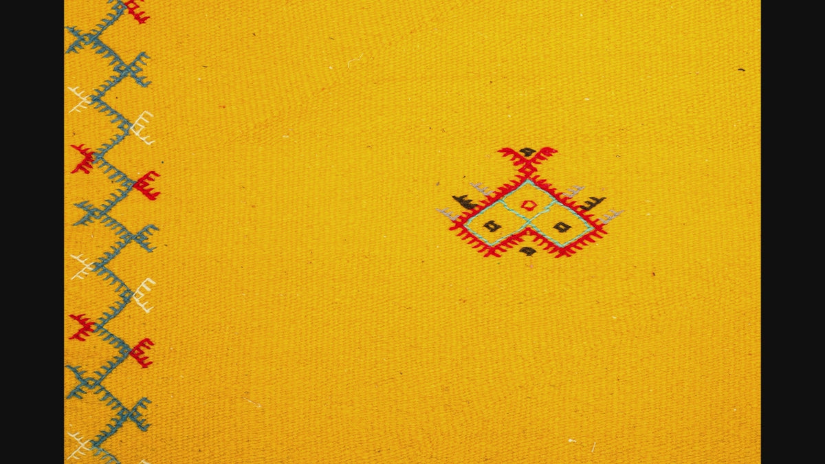 close-up video of a yellow moroccan rug handwoven with hand embroidered motifs