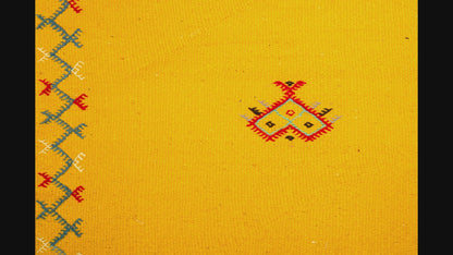 close-up video of a yellow moroccan rug handwoven with hand embroidered motifs