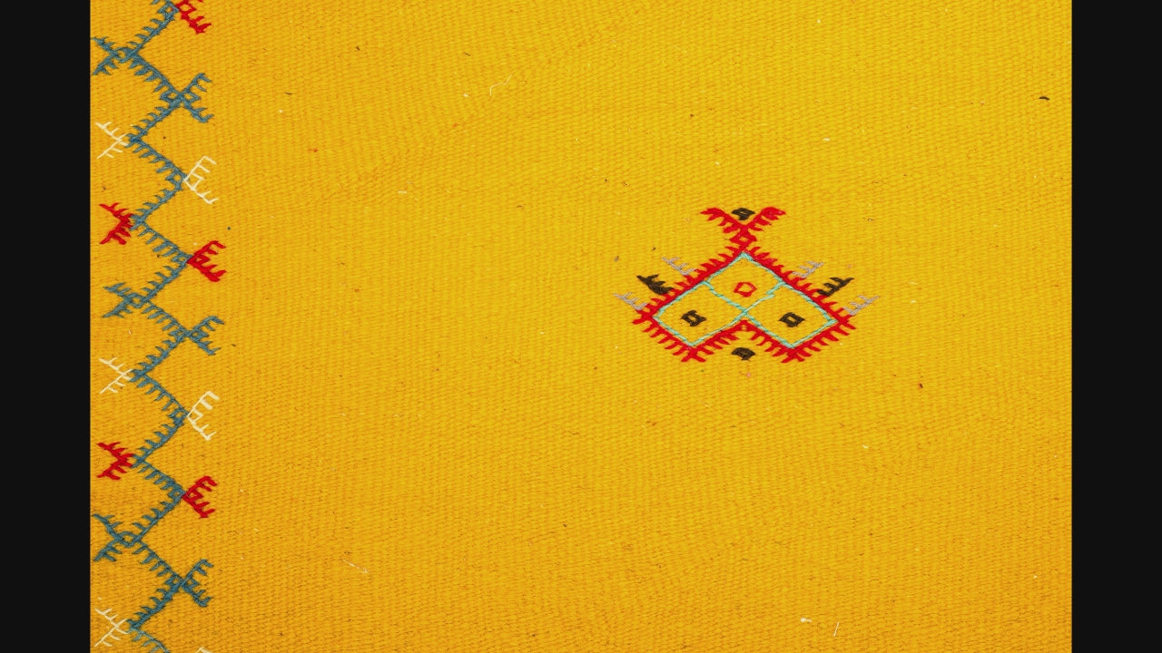 close-up video of a yellow moroccan rug handwoven with hand embroidered motifs