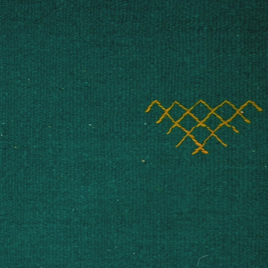 video close-up of a green moroccan rug handwoven with hand embroidered tribal motifs