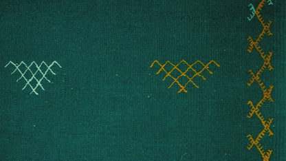 video close-up of a green moroccan rug handwoven with hand embroidered tribal motifs